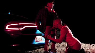 Bald man with tattoos is banged next to the vehicle