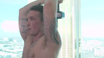 Tattooed man works out with weights and a submissive fella