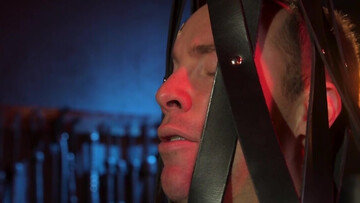 Tied up behind bars and getting his erect cock jerked off